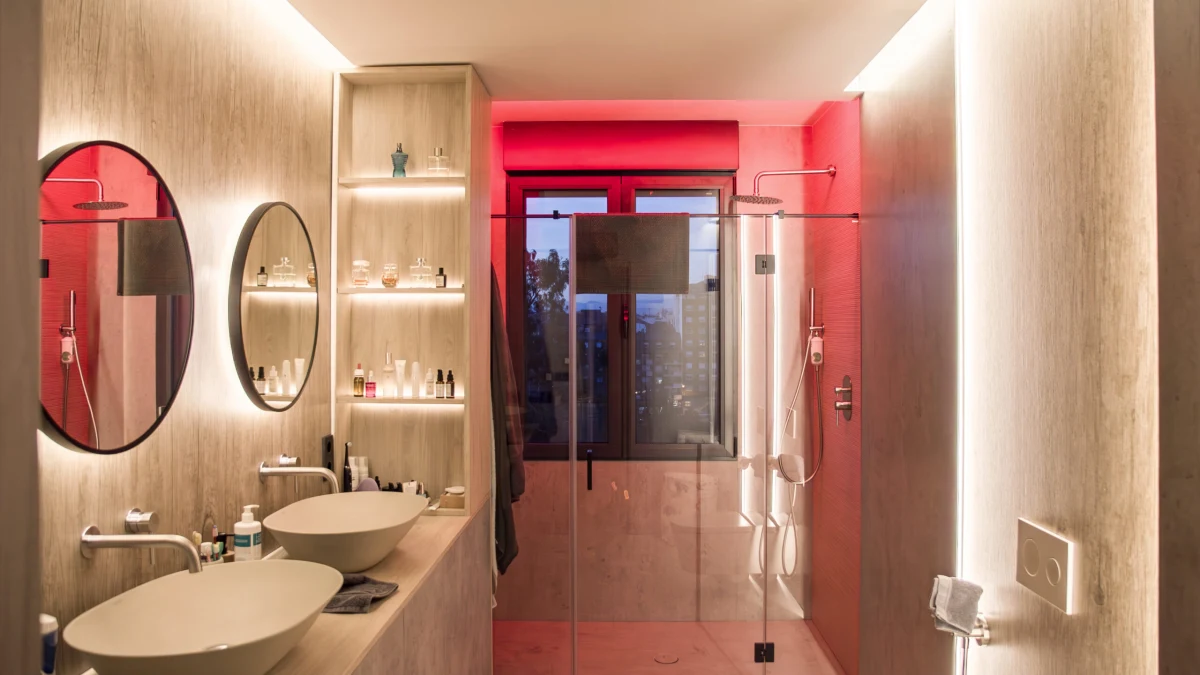 Baño de Casa JR con dos lavabos e iluminación de color en la ducha