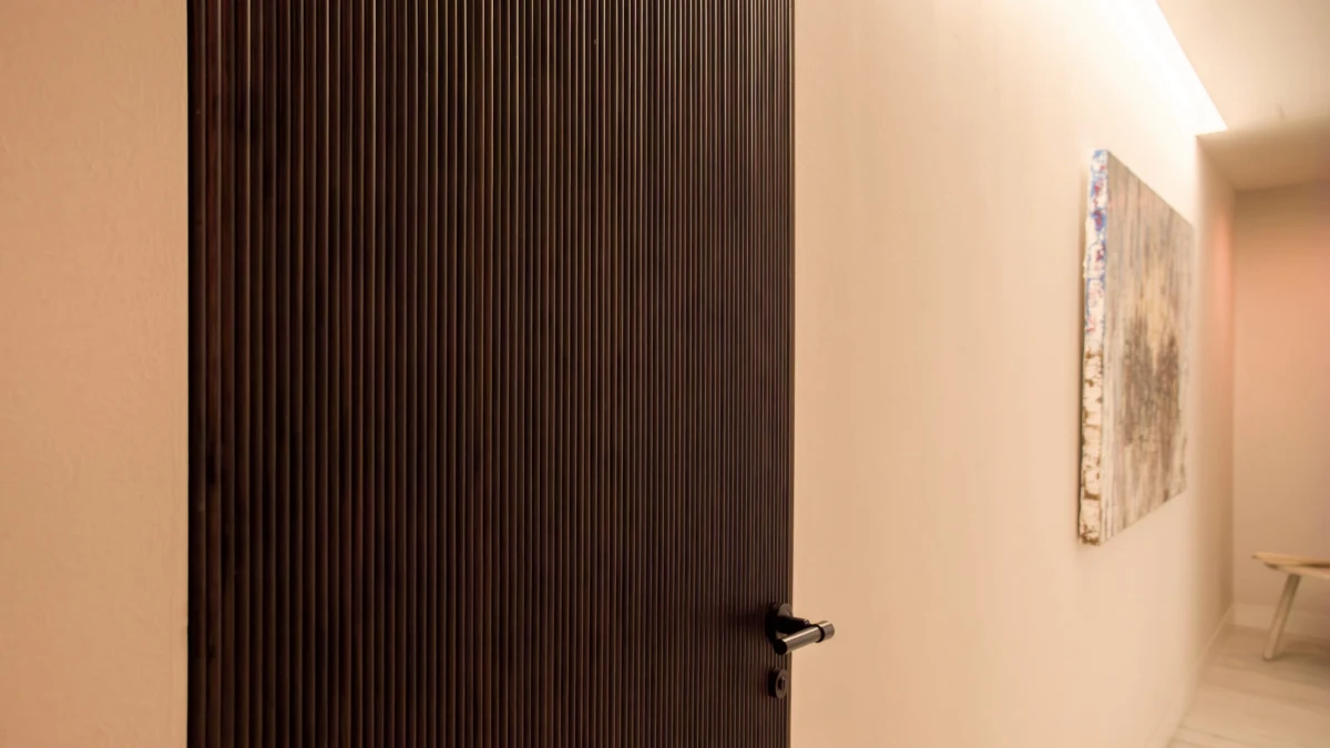 Puerta de madera y pasillo iluminado de Casa JR