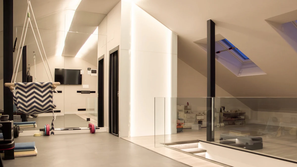 Gimnasio abuhardillado de Casa JR con equipamiento de ejercicio