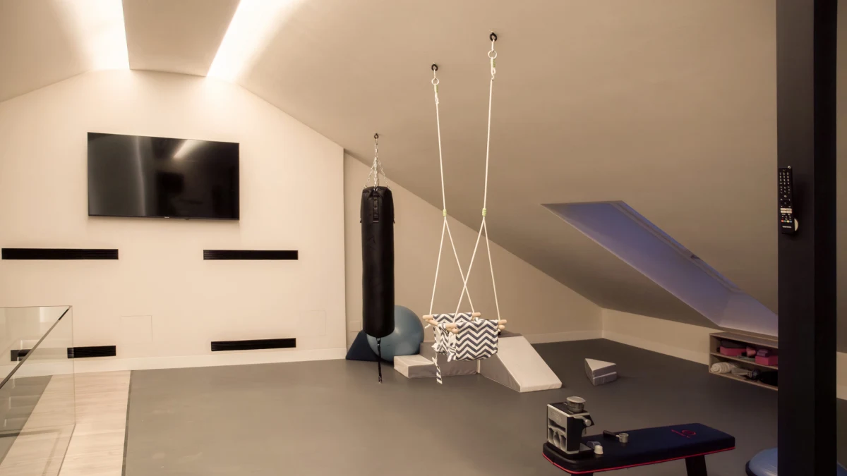Gimnasio abuhardillado de Casa JR con equipamiento de ejercicio